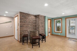 A room with a stone accent wall, a wooden barrel, and two stools. - A Shore Thing: Private Pool, Hot Tub, Elevator, Currituck Club Amenities (Corolla)