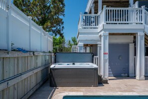 A hot tub in front of a building with a white fence and a balcony. - A Shore Thing: Private Pool, Hot Tub, Elevator, Currituck Club Amenities (Corolla)