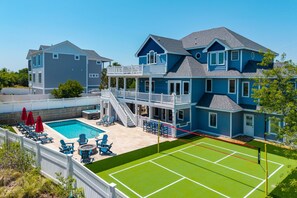 A two-story house with a swimming pool, outdoor seating, and a tennis court. - A Shore Thing: Private Pool, Hot Tub, Elevator, Currituck Club Amenities (Corolla)