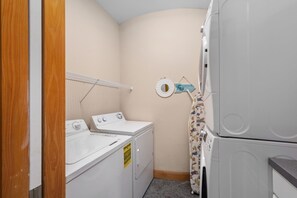 A laundry room with a washer, dryer, and a rack.