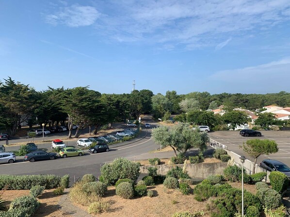 A parking lot with several cars, surrounded by trees and greenery.