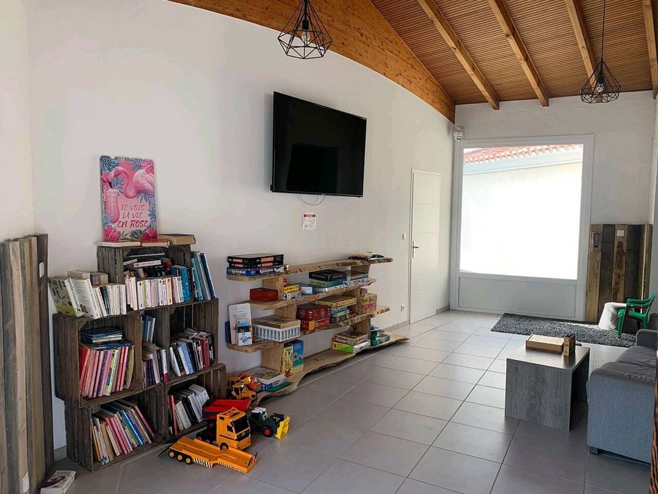 A living room with a TV, bookshelves, toys, and a sofa.