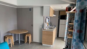 Una cuina compacta amb zona de menjador, nevera petita i forn integrat.