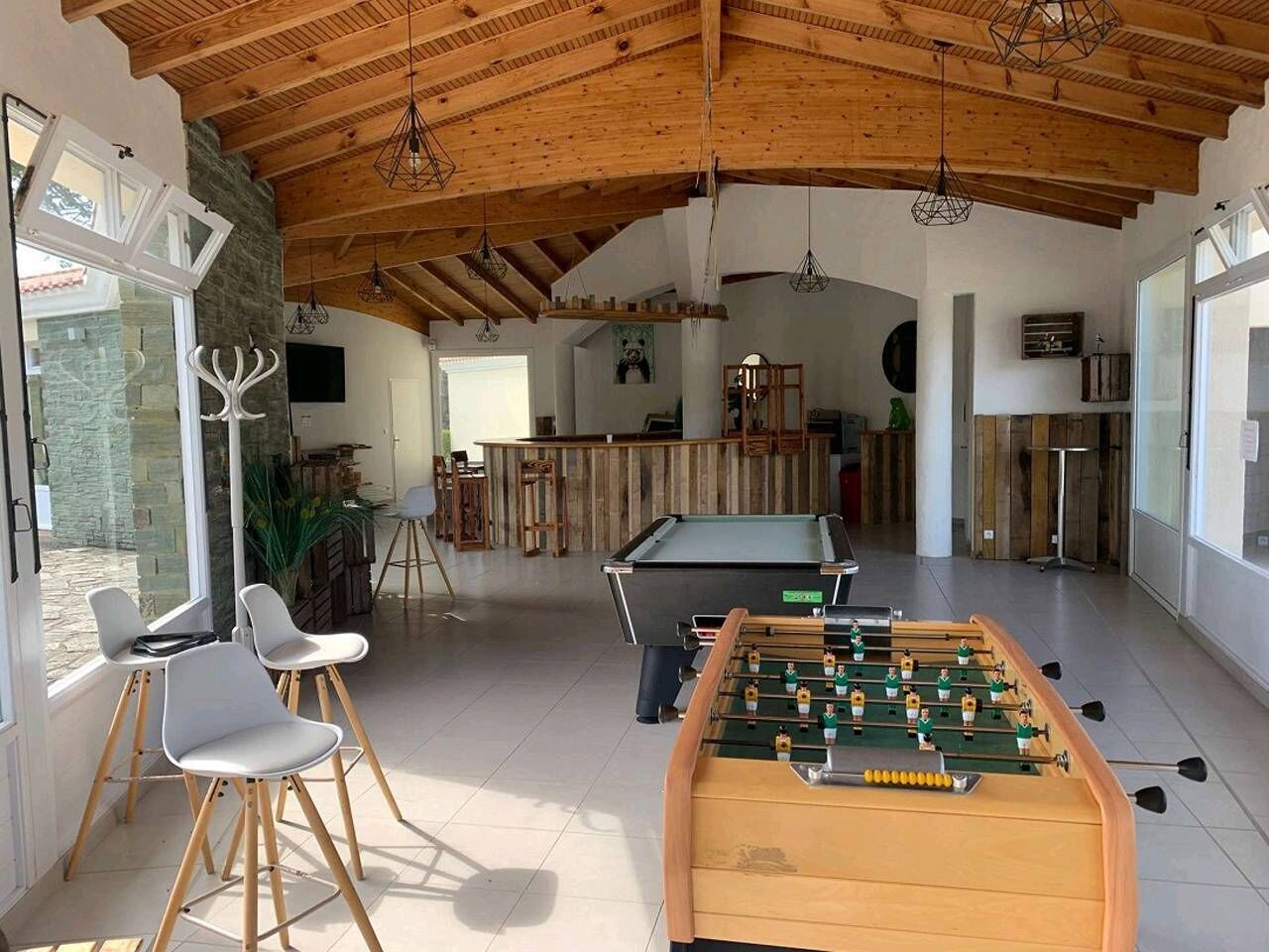 A spacious indoor area with a foosball table, seating, and a pool table.