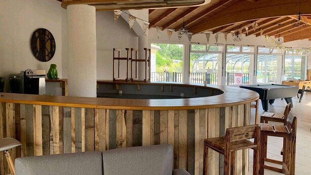 Zona de bar amb un mostrador de fusta, seients i billar.