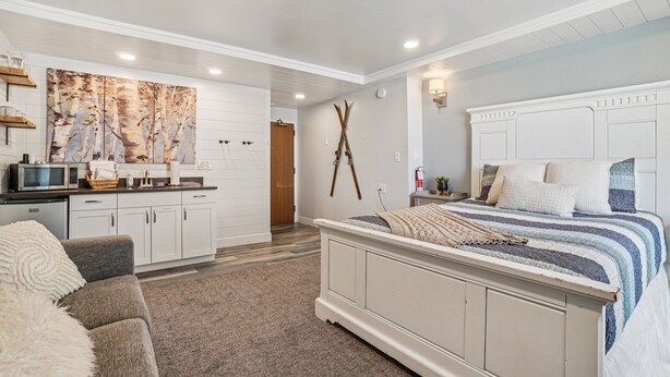 A bedroom with a large bed, a dresser, a vanity, and a painting on the wall.