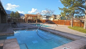 A backyard with a swimming pool, patio furniture, and a wooden deck.