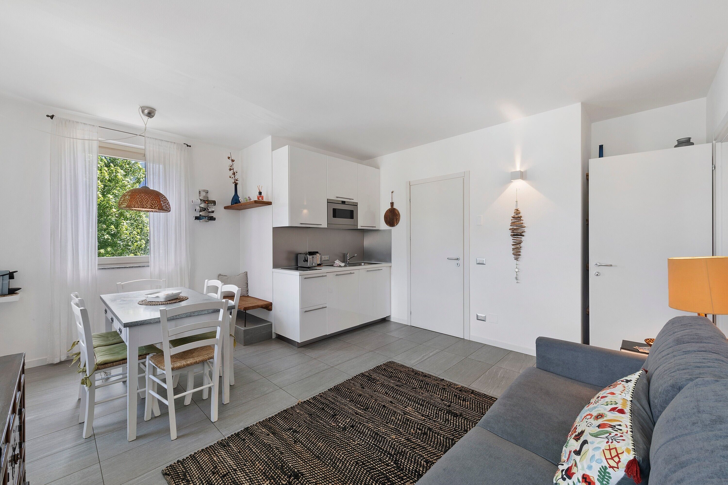 Een moderne keuken met witte kastjes, een eettafel met stoelen, een bank en een tapijt met een patroon.