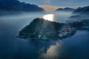Vista aérea de un pueblo a orillas de un lago, con edificios y montañas al fondo.