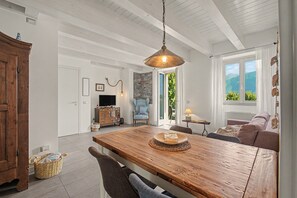Un comedor amplio con una mesa de madera, una lámpara colgante y vistas al exterior a través de una ventana.