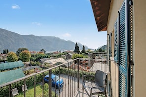 A balcony with a view of a lake and mountains, a blue car parked, and a chair. - Apartment 'Aurora' with Lake View, Wi-Fi and Air Conditioning (Bellagio)