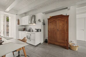 Una cocina con armarios blancos, una puerta de madera y un comedor con mesa y sillas.