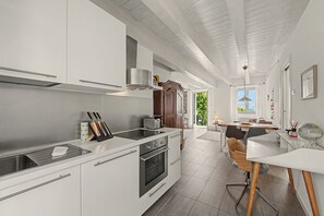 A modern kitchen with white cabinetry, a built-in oven, and a dining area with a table and chairs. - Apartment 'Aurora' with Lake View, Wi-Fi and Air Conditioning (Bellagio)