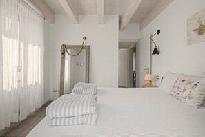 A bedroom with a large bed, a mirror with a rope decoration, a bedside lamp, and a door leading to another room. - Apartment 'Aurora' with Lake View, Wi-Fi and Air Conditioning (Bellagio)