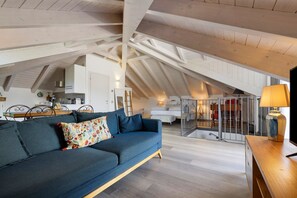 A loft-style room with a high ceiling, a sofa, a dining table, and a staircase. - Apartment 'Brezza' with Lake View, Wi-Fi and Air Conditioning (Bellagio)