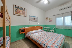 A room with a wooden bed, a green wall, a small table, and a window with curtains. - Il Marchese Mirante 'Room 3' with Shared Garden, Wi-Fi and Air Conditioning (san pietro in bevagna)