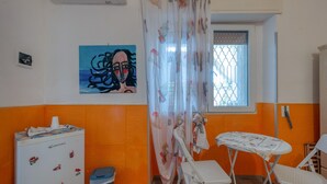 A room with a refrigerator, a table with chairs, a window with a view, and a painting on the wall. - Il Marchese Mirante 'Room 4' with Shared Garden, Wi-Fi and Air Conditioning (san pietro in bevagna)