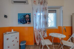 Une pièce avec un réfrigérateur, une table et des chaises, une fenêtre donnant sur un beau paysage et un tableau accroché au mur.