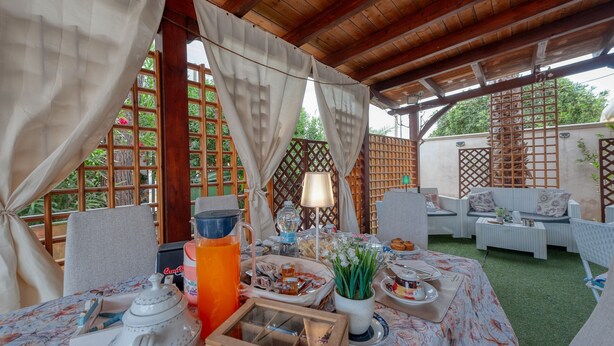 An outdoor dining area with a table set for breakfast, a wooden pergola, and a view of greenery. - Il Marchese Mirante 'Room 4' with Shared Garden, Wi-Fi and Air Conditioning (san pietro in bevagna)
