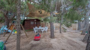 Une cabane en bois avec un espace de jeux, comprenant une balançoire et une table avec des chaises.