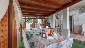 An outdoor dining area with a table set for two, covered with a floral tablecloth, and surrounded by wooden furniture. - Il Marchese Mirante 'Room 4' with Shared Garden, Wi-Fi and Air Conditioning (san pietro in bevagna)
