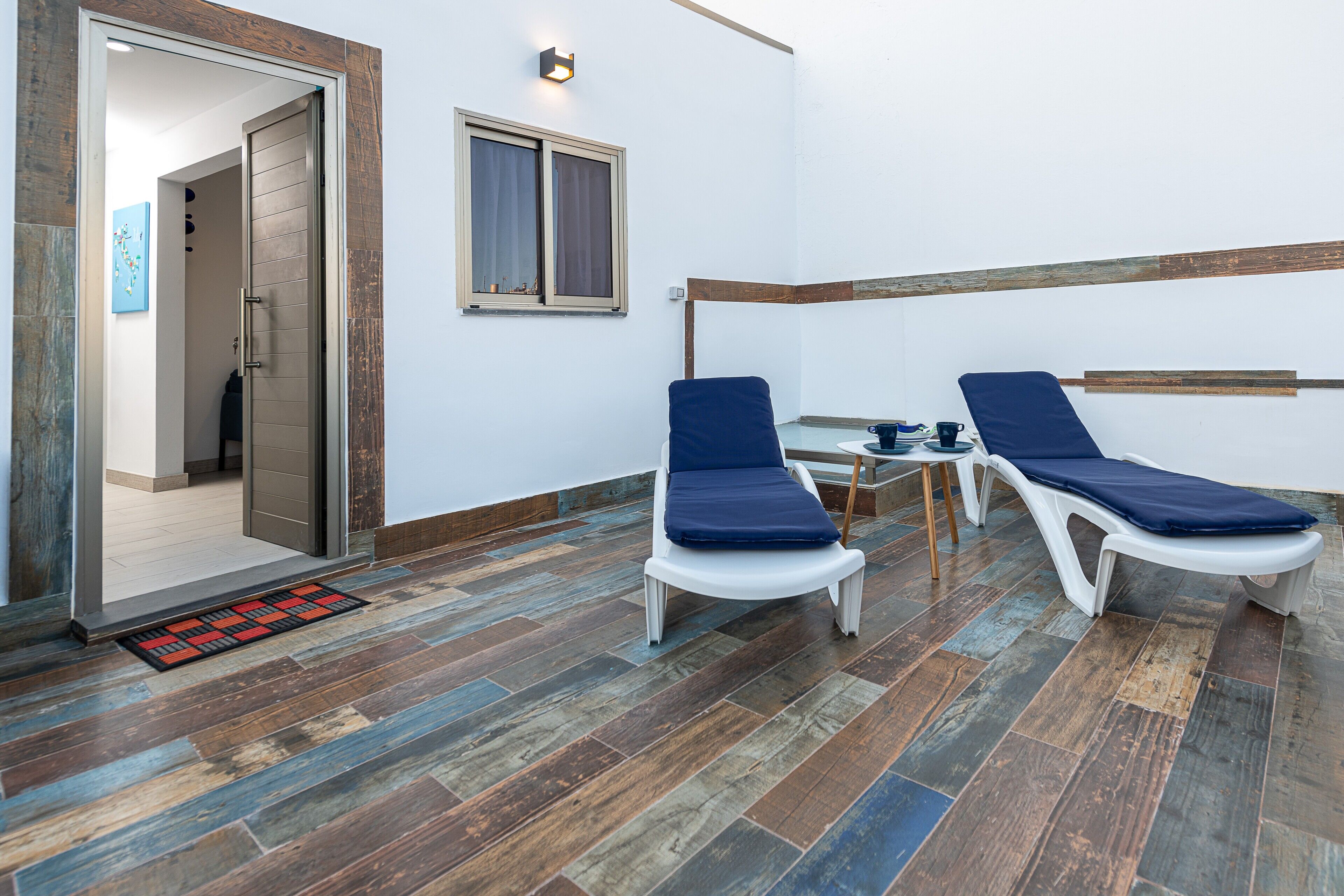 Ein Zimmer mit zwei Lounge-Sesseln, einem kleinen Tisch und einem Fenster.