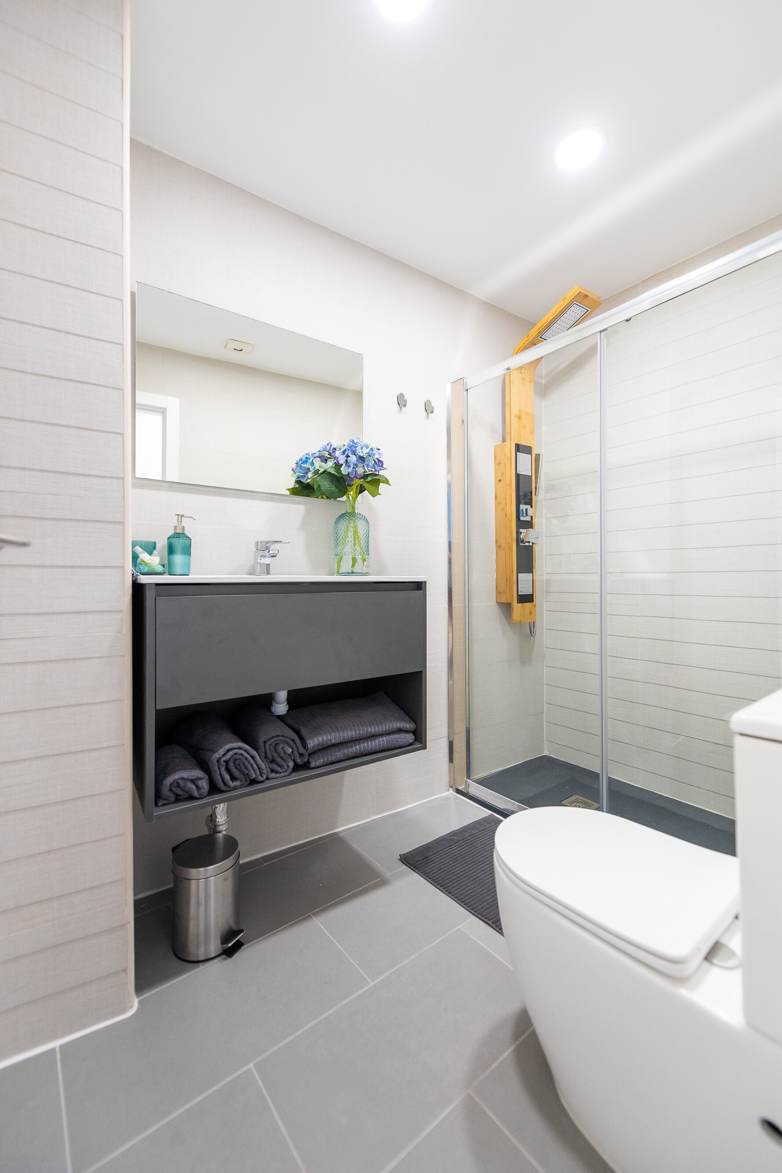 Un bagno moderno con il water, una doccia con porta in vetro, un lavandino con specchio e un porta asciugamani.