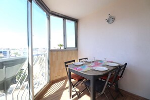 A dining area with a table set for four, a window with blinds, and a view of a cityscape.
