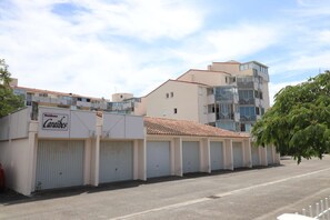 A residential building with multiple garage doors, a sign reading 'Residence Cariibes,' and a clear sky.