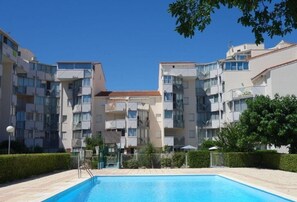 A modern apartment building with a swimming pool in the foreground.