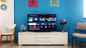Un téléviseur à écran plat posé sur un meuble télé blanc, avec une sélection de services de diffusion en continu affichée.