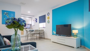 Un salon moderne avec un canapé, un téléviseur et un coin repas à l’arrière-plan.