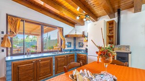Uma cozinha com armários de madeira, uma janela grande com cortinas e uma mesa de jantar com pão.