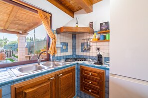 Une cuisine avec un plafond en bois, une fenêtre avec un rideau, un évier, une cuisinière et des placards.