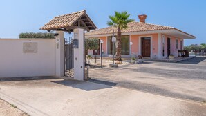 Uma entrada gradeada para um edifício com telhado de telhas e uma palmeira em primeiro plano.