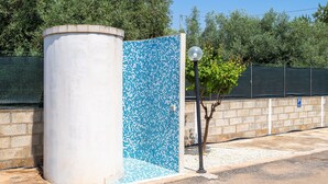 Een blauw betegelde muur, een cilindervormige betonnen constructie, een kleine boom en een parkeersbord.