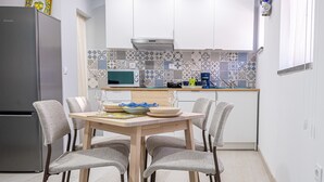 A modern kitchen with a dining table, chairs, and a refrigerator.