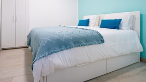 A bedroom with a bed, white wardrobe, and light blue walls.