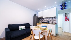 A modern kitchen with white cabinets, a black sofa, and a dining table with chairs. - Vacation 'Amalfi' with Wi-Fi (Corralejo)