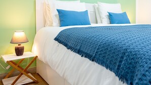 A neatly made bed with white and blue bedding, a bedside lamp, and a striped nightstand. - Vacation 'Amalfi' with Wi-Fi (Corralejo)