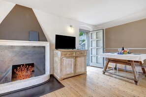 Una habitación con chimenea, televisor, un aparador de madera y una mesa de comedor con mantel blanco.
