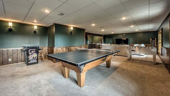 A pool table in a room with green walls and wooden paneling.