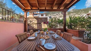 A wooden table set for breakfast with plates, cups, and a basket of pastries. - Holiday home with veranda in the inner courtyard (Cala Gonone)