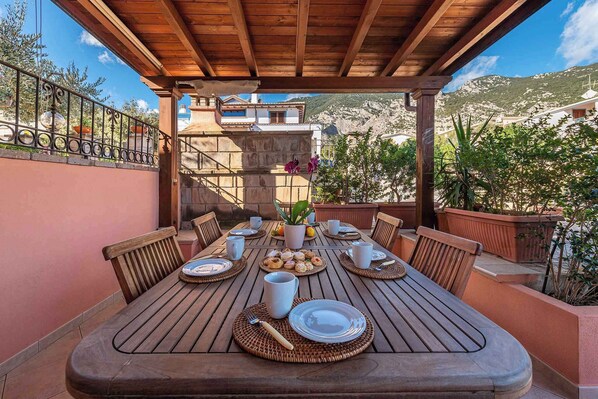 Une table en bois, dressée pour le petit-déjeuner, avec des assiettes, des tasses et un panier de viennoiseries.