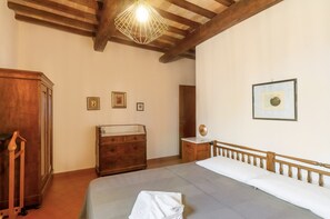 A bedroom with a bed, wooden dresser, and a hanging light fixture.