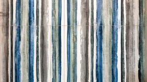 Een muur met verticale strepen in verschillende blauwe, groene en grijze tinten.