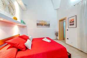 Una camera da letto con una coperta rossa, una testiera in legno e un quadro raffigurante un albero appeso al muro.
