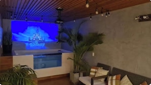 A room with a Disney-themed TV screen, a pool, and a seating area with cushions. - Delightful 1, 2 o 3 bedroom apartment in Ica (Ica)