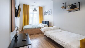 Camera d'albergo compatta con un letto, un comodino e una piccola scrivania.
