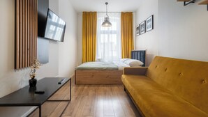 Una camera da letto moderna con un letto, un divano, una TV e una scrivania.